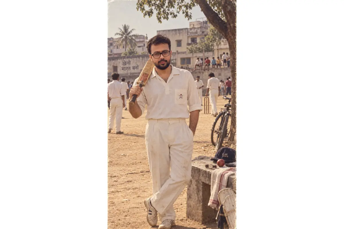 Young Indian man holding a cricket bat on a dusty neighborhood cricket ground in 1980s India